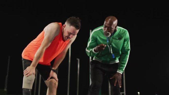 多样化的男教练和疲惫的残疾男运动员与奔跑的刀片说话