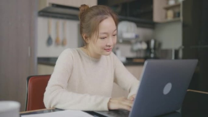 美丽的亚洲年轻女子年龄36岁，早上在家用笔记本电脑工作。成人在线学习概念。与阿尔法香奈儿。
