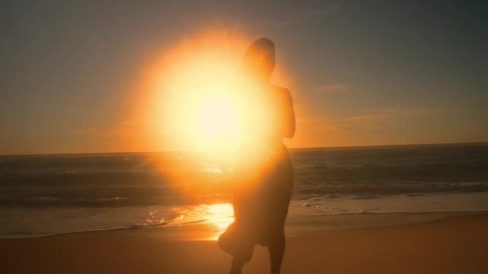 日落时在海滩上跳舞的年轻女子的剪影
