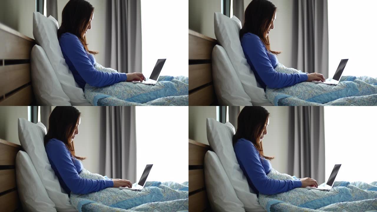 亚洲妇女在床上使用笔记本电脑