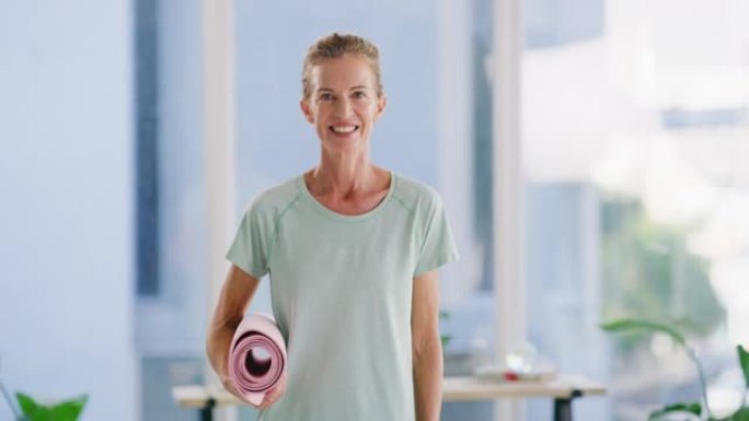 活跃的成熟女人在健身室或家里拿着瑜伽垫。一位自信微笑的高加索女士的肖像感到开朗，满足和兴奋，享受轻松