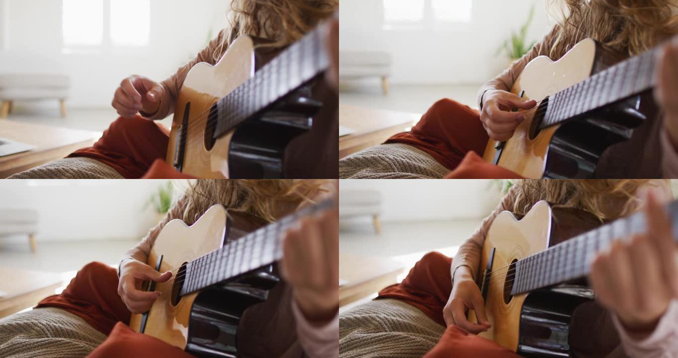 白人妇女的中段演奏原声吉他，坐在阳光明媚的小屋客厅