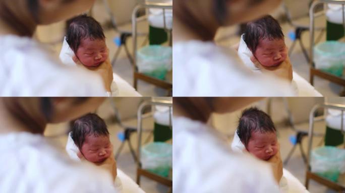 医院里一名亚裔妇女抱着她刚出生的男婴。她在这里斜躺着，把孩子抱在胸前安慰他。