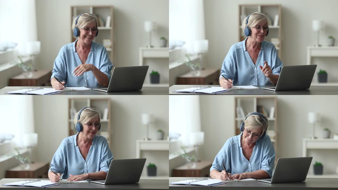 迷人的老年妇女戴着耳机参加在线课程
