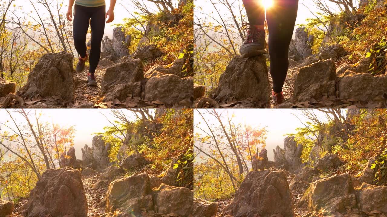 低角度: 无法辨认的女人在金色的秋天日出时爬上一条岩石小径。