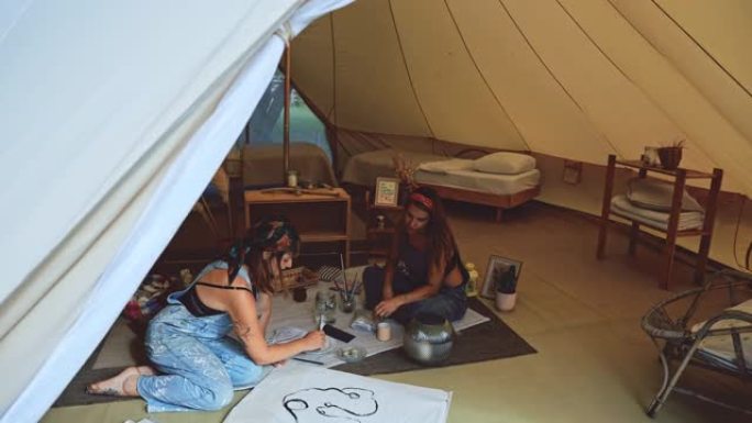 WS两名年轻妇女在帐篷内用画笔画画