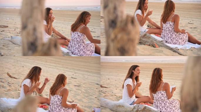 WS两名妇女在日落时在海滩上喝玫瑰酒