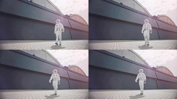 一位自信英俊的宇航员的低角度镜头正从工业金属墙走向相机。明亮的色彩校正。穿着未来派西装的人，手上有技