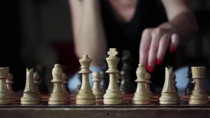冠状病毒封锁期间，一名女子在家下棋。将所有白色棋子放在开始位置的棋盘上。4k分辨率。