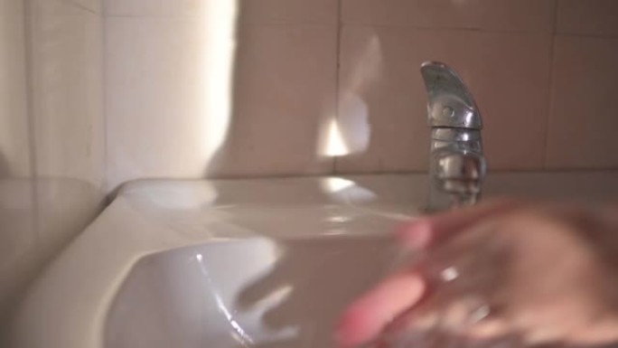亚洲中国中年妇女在洗手间用肥皂在水龙头洗手
