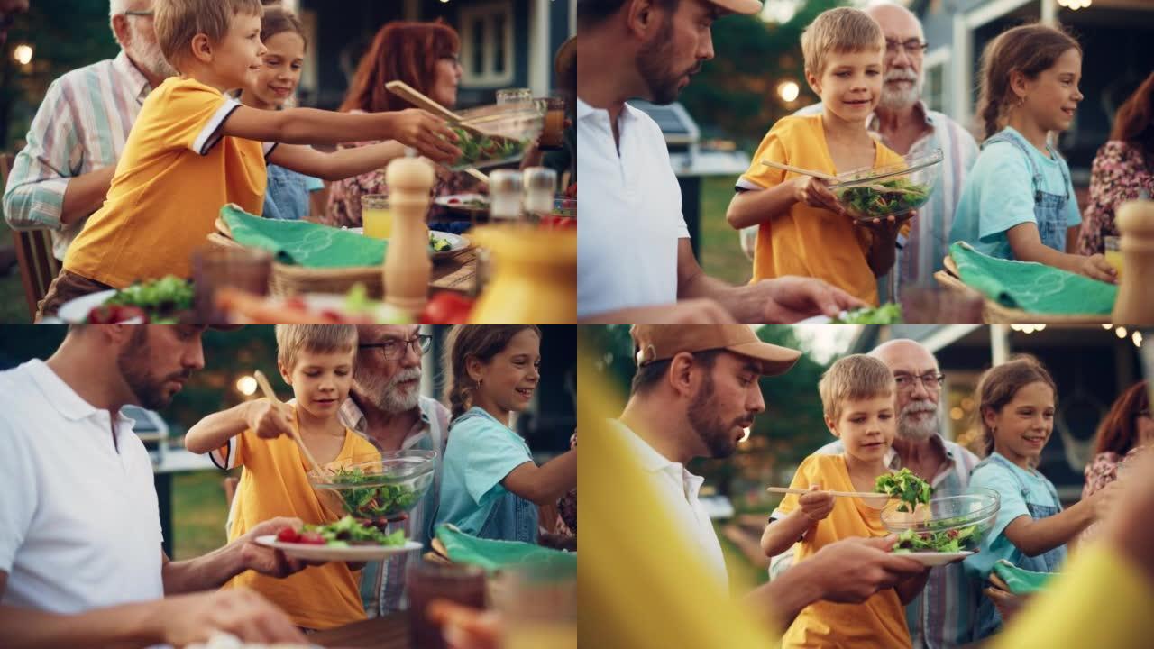 小男孩拿起一碗美味的素食沙拉，配以叶子和樱桃番茄。儿子把纯素食放在盘子里给他父亲吃。与家人共进花园晚