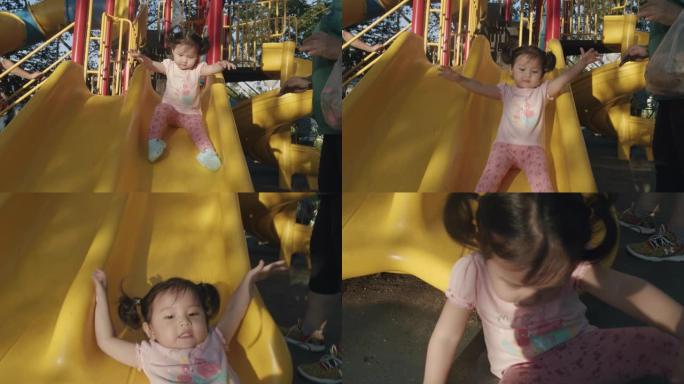 亚洲蹒跚学步2岁的孩子喜欢夏天和她的祖父和祖母在公园的户外操场上玩滑梯