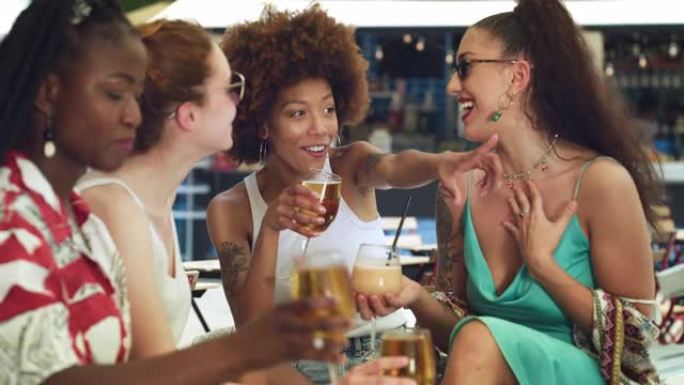 不同的女性朋友在夏季旅行中庆祝和欢呼快乐的回忆。一群多民族妇女在露天酒吧举杯为友谊干杯