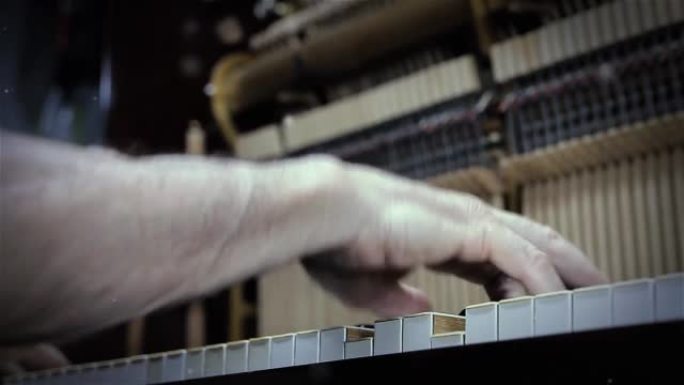 男子在他的钢琴工作室调音一架旧钢琴。特写。