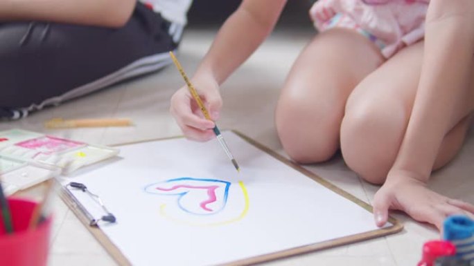 特写亚洲小女孩在家时在客厅手工绘画和绘画她的艺术和工艺。她喜欢用水彩和画笔在白纸上创作艺术作品，并从