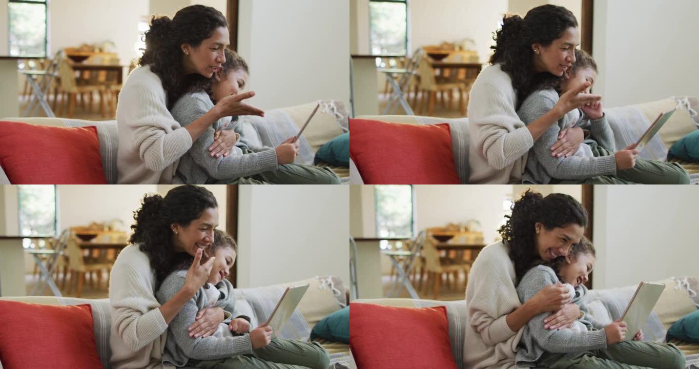快乐的混血母女坐在沙发上，玩得开心，用平板电脑