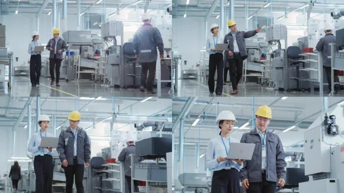 两名年轻的亚洲重工业工程师戴着安全帽，带着笔记本电脑在工厂里散步。两名在生产工厂工作的制造员工的慢动