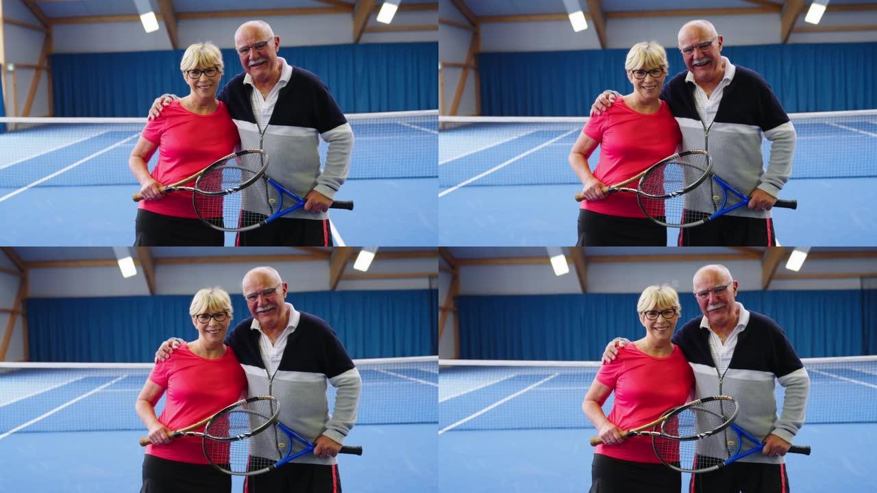 幸福的高级夫妇网球运动员站在硬地球场上的肖像