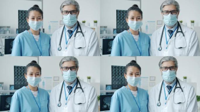 穿着制服和面罩站在医院病房的男女医学专家的慢动作肖像