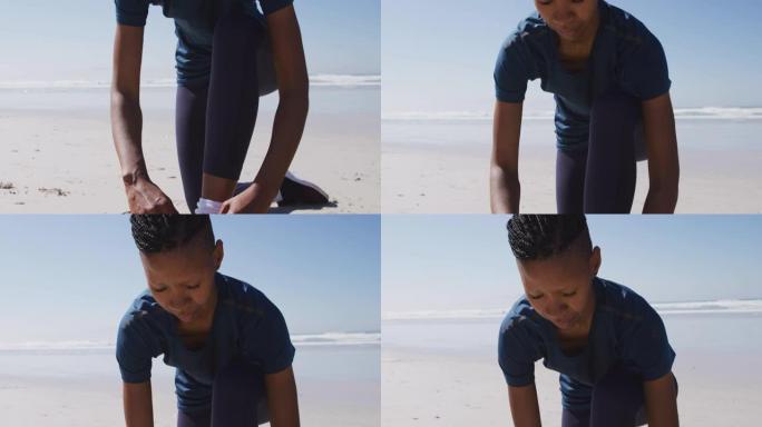 非裔美国妇女在沙滩和蓝天背景上系鞋带