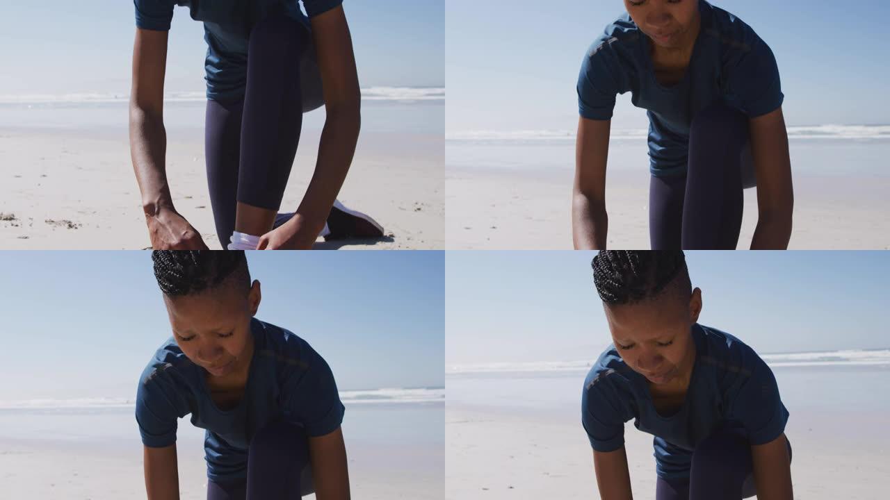 非裔美国妇女在沙滩和蓝天背景上系鞋带