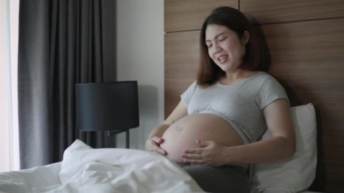 孕妇在家里的卧室里对肚子里的婴儿充满了爱意和快乐