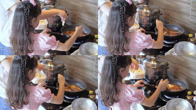 小女孩在家里的厨房里和母亲一起做饭