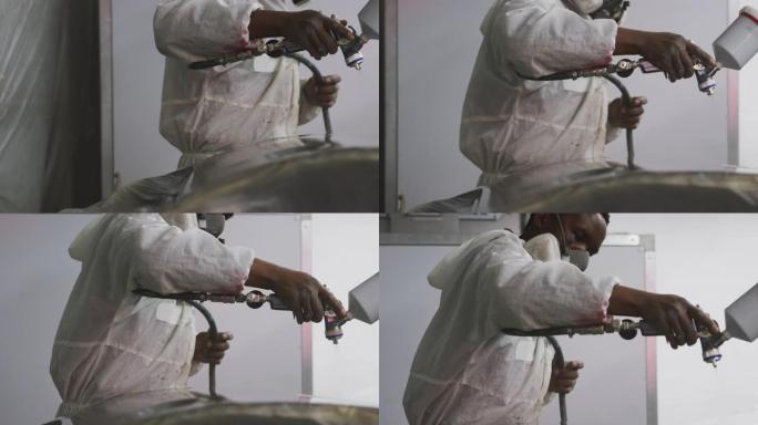 非裔美国男汽车修理工穿着西装用喷枪画一辆汽车