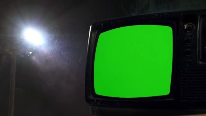 旧电视机在雨中绿屏。放大。