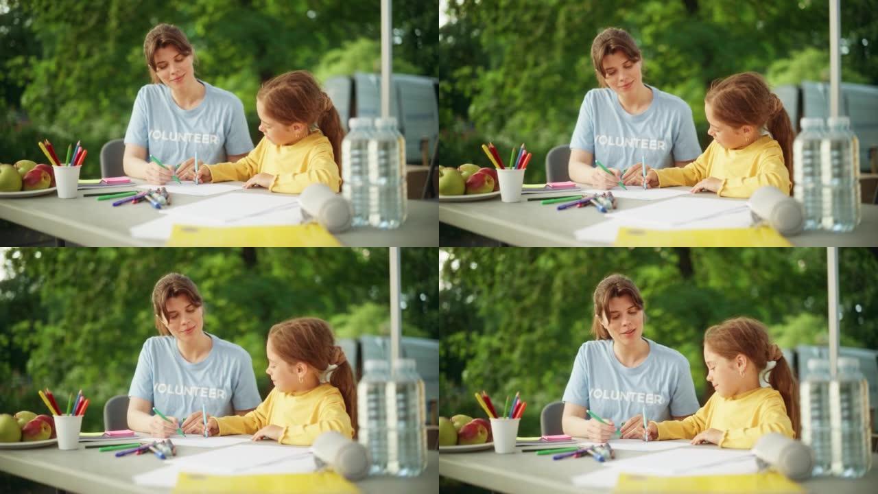 当地人道主义援助组织的志愿者教一个才华横溢的小女孩用五颜六色的蜡笔画画。快乐的孩子和慈善工作者在幼儿