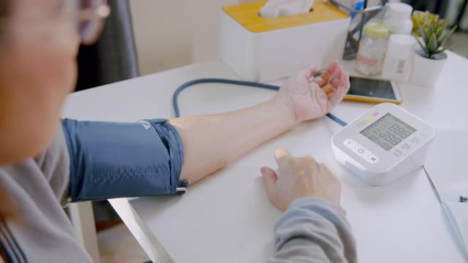 老年妇女使用医疗器械在家检查血压计和心率。