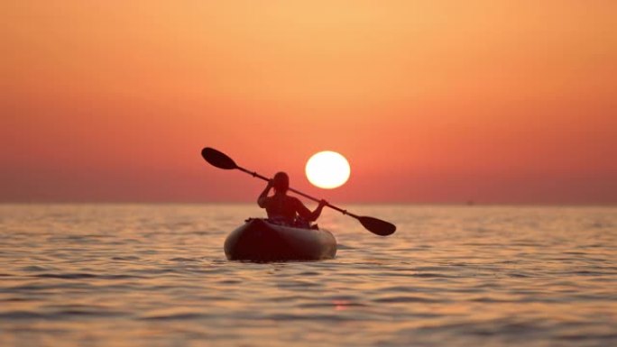 克罗地亚亚得里亚海日落时，WS剪影年轻女子在宁静的海洋上划桨船