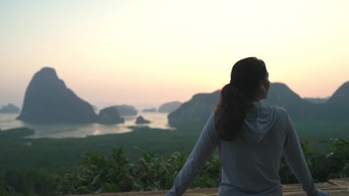 亚洲体育女子站在山顶，在日落时欣赏壮丽的景色