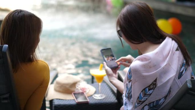 两个女人在游泳池里聊天显示智能手机