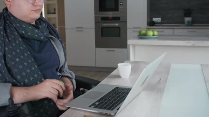 坐在轮椅上的男子在电脑上吃零食