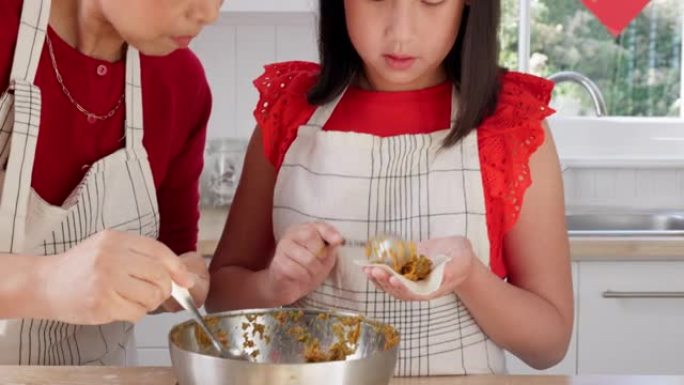 母亲教孩子在家里的中国假期在厨房做饭。妈妈和女儿在中国的家中一起做传统的晚餐，参加聚会或活动。