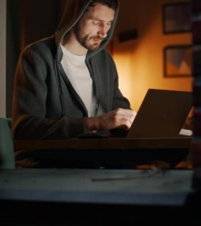 垂直屏幕: 白人男子坐在家庭办公室的办公桌前在笔记本电脑上工作。自由企业家听音乐，做远程工作。穿过公