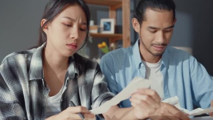 压力亚洲夫妇男女使用计算器计算家庭预算，债务，家庭经济危机期间的每月开支。