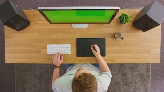 男性平面设计师或照片润饰师的俯视图，图形平板电脑在电脑上工作，创意办公室绿屏-慢动作拍摄