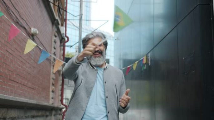 在现代城市中，激动的成熟男人挥舞着巴西国旗并在外面微笑的肖像
