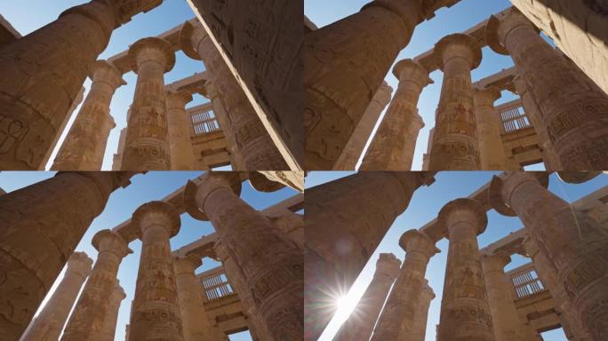埃及卢克索的卡纳克神庙。雄伟的柱子上有古埃及的图画，太阳从柱子后面出来
