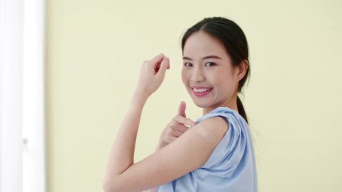 年轻的亚洲妇女在隔离背景下接种疫苗后露出手臂