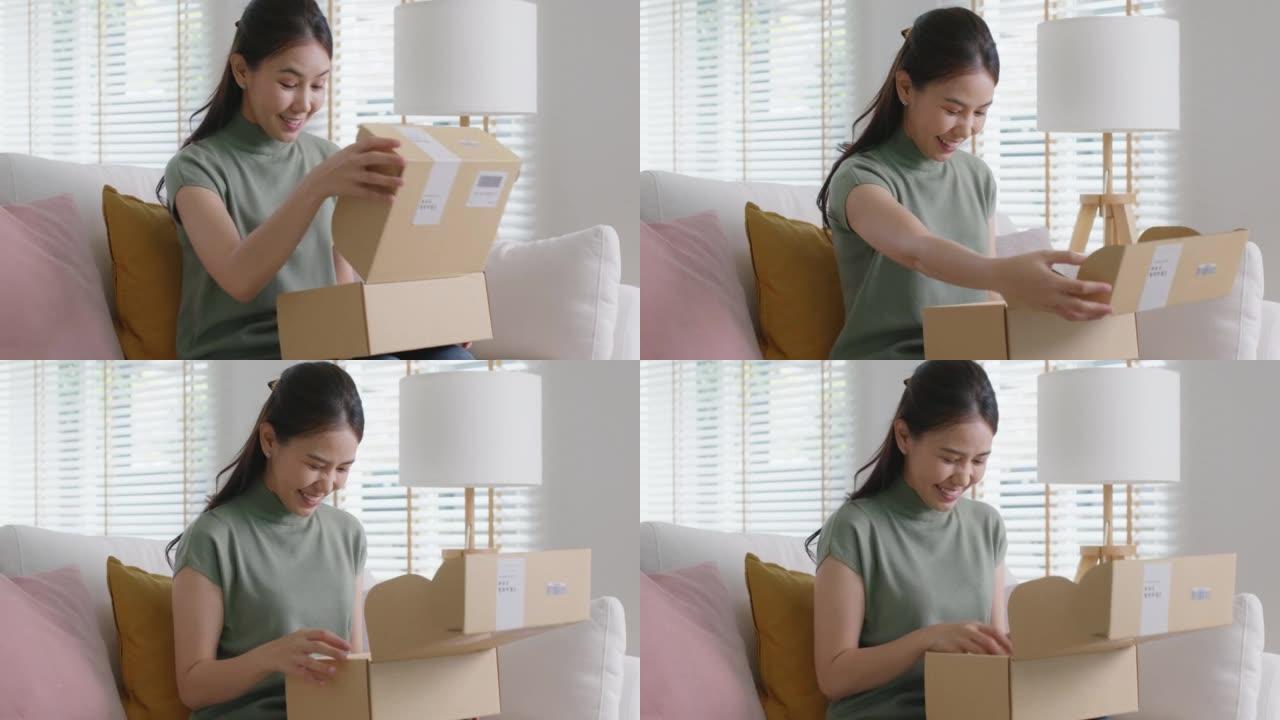 亚洲女人快乐打开快递箱在家网上购物。