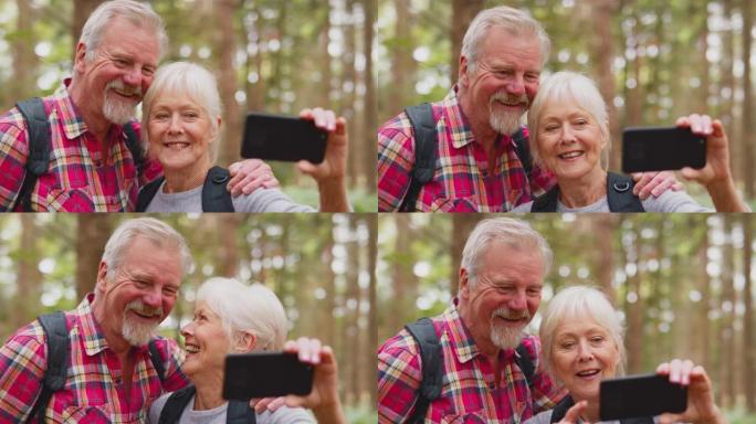 退休的高级夫妇在森林乡村漫步时用手机摆姿势自拍-慢动作拍摄