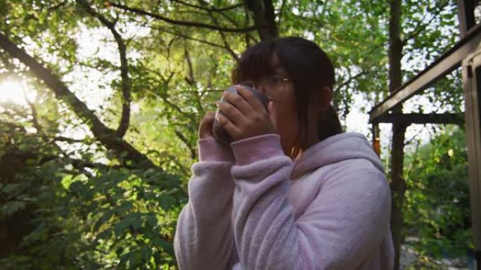 亚洲女孩在花园里喝茶，微笑着