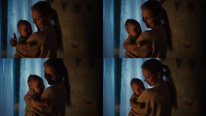 快乐的母亲晚上在舒适的黑暗儿童卧室里抱着一个可爱的新生婴儿。有爱心的妈妈和幼儿在家里结为纽带。童年、