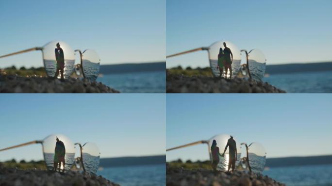 夫妇在海滩拥抱太阳镜中的倒影