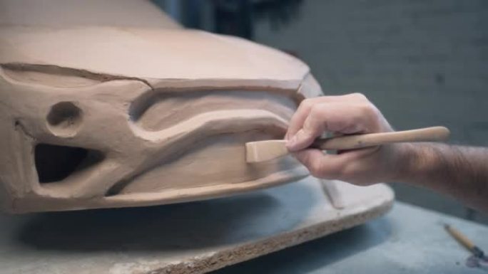 设计师的手使用雕刻工具处理汽车雕塑的细节