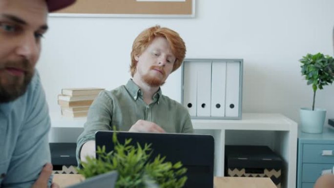 英俊的红发男人在坐纸飞机时的肖像，同事在办公室谈论工作