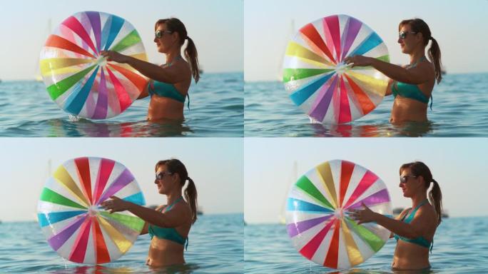 特写: 微笑的女人在海洋中玩耍，手里拿着一个大球。